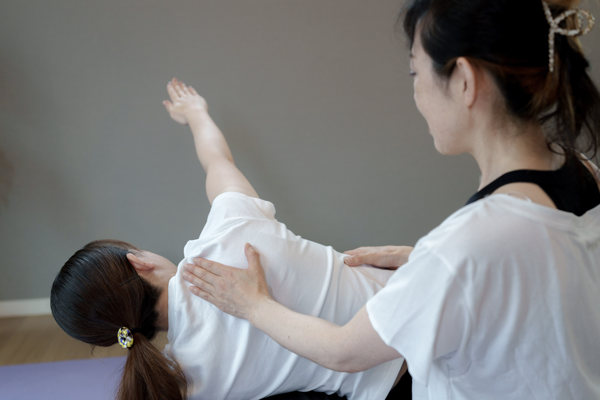 横向きに寝た方の身体に手を添え、腕を伸ばす動きをサポートしている様子